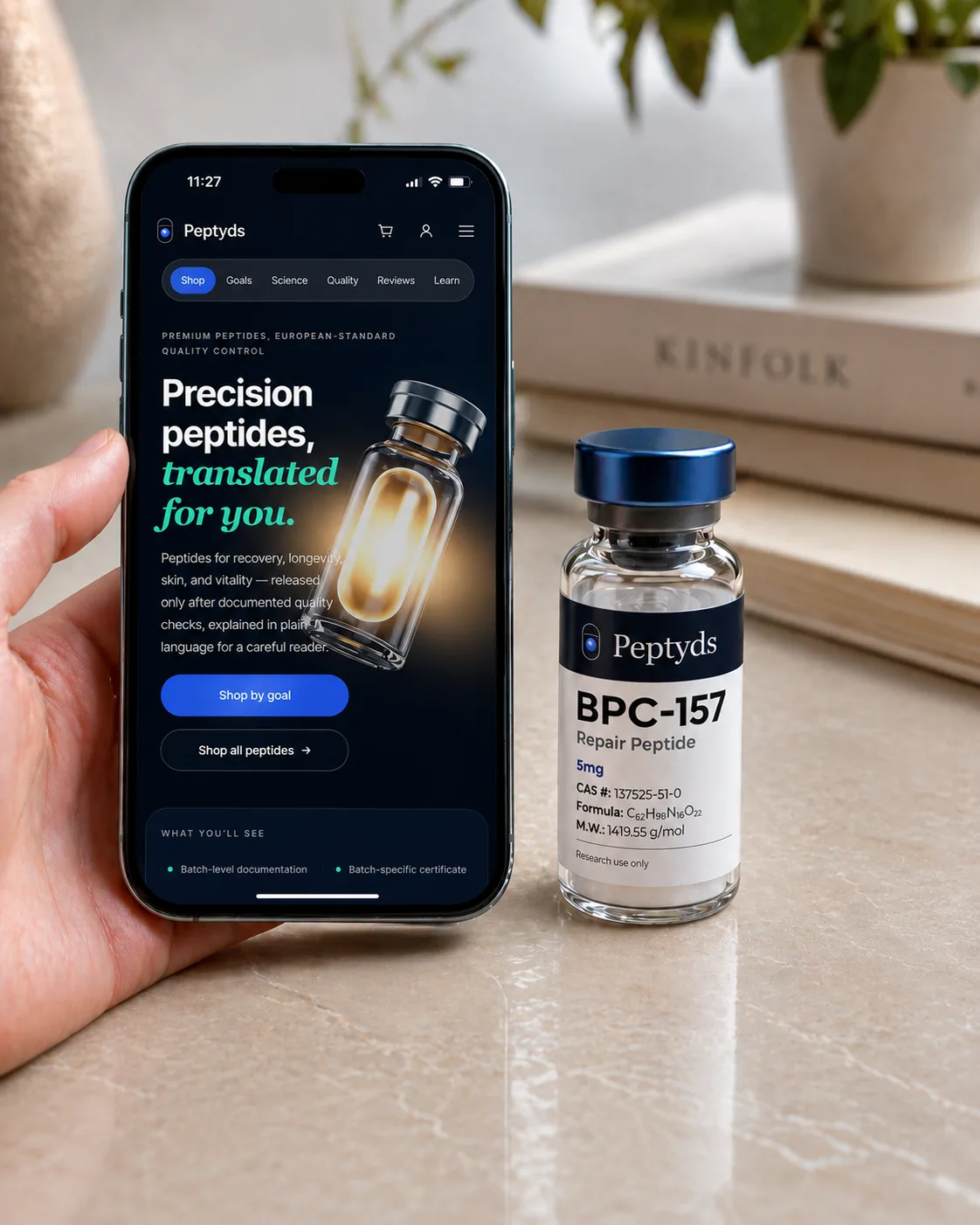 Hand met telefoon: Peptyds-homepage in beeld naast een echte BPC-157 5 mg vial op een marmeren aanrecht